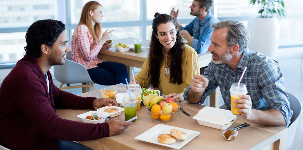 Coworkers chatting over fruit and bagels.