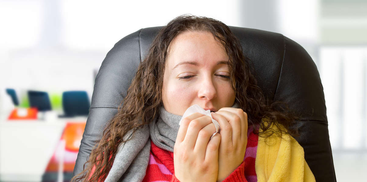 Ill woman sneezing at the office.