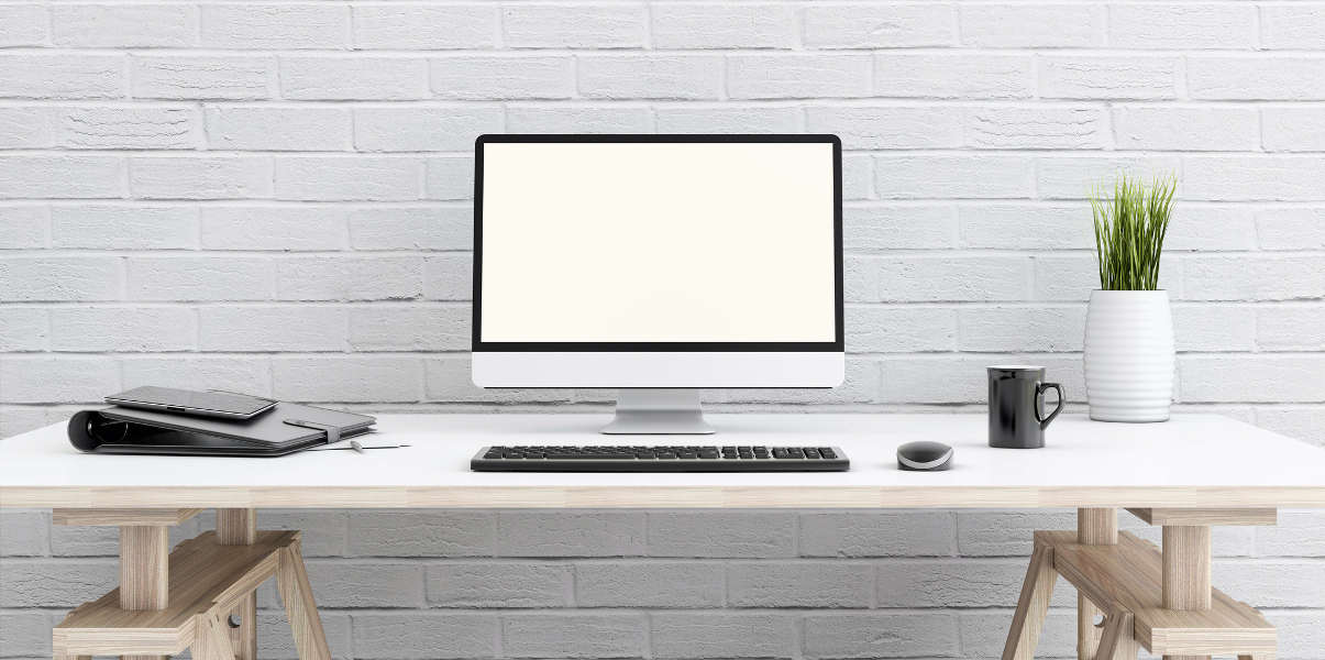 White computer desk against white brick wall.