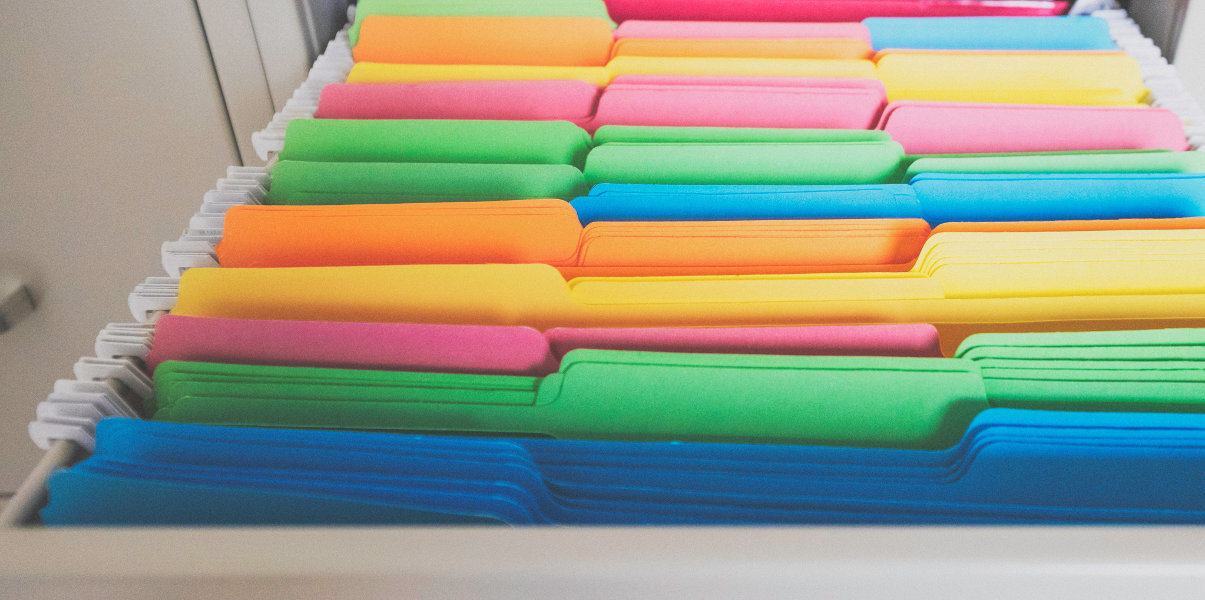 Close-up of colorful file folders in file cabinet drawer.