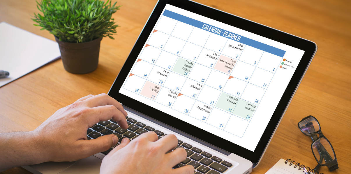 Hands typing on a laptop with a calendar planner on screen