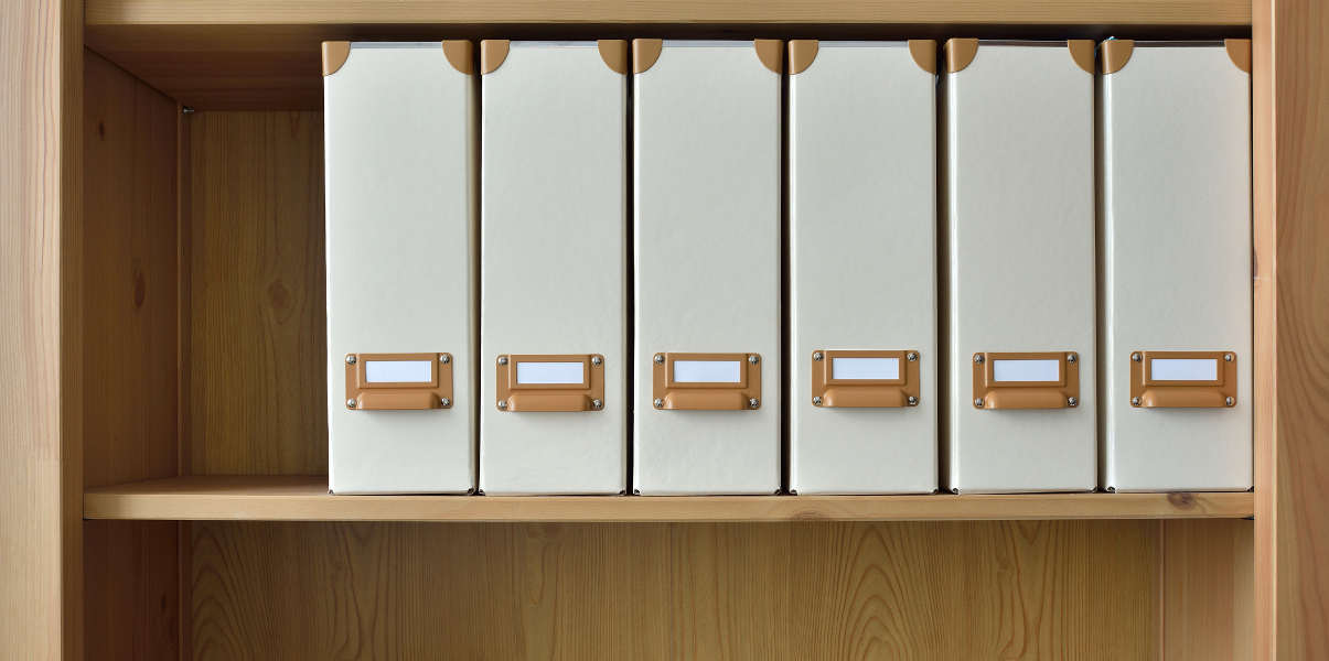 Wooden office shelving with cream folders.