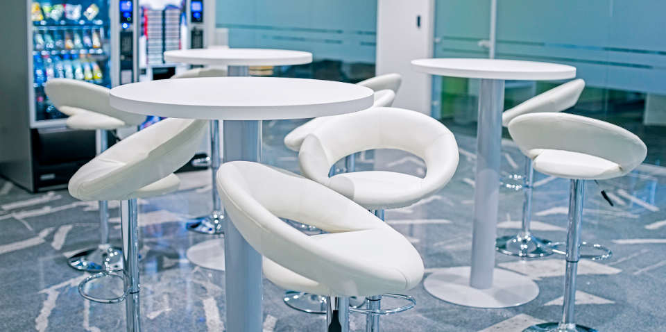 Stylish break area with white leather stools and vending machine.